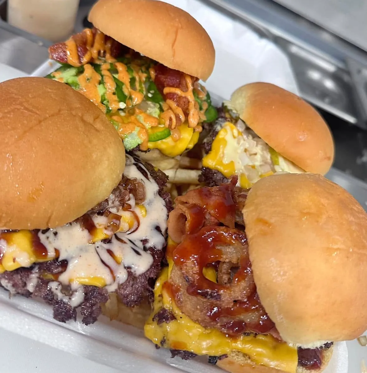 Assorted Wanna Smash burgers with cheese, bacon, jalapenos, and house sauces