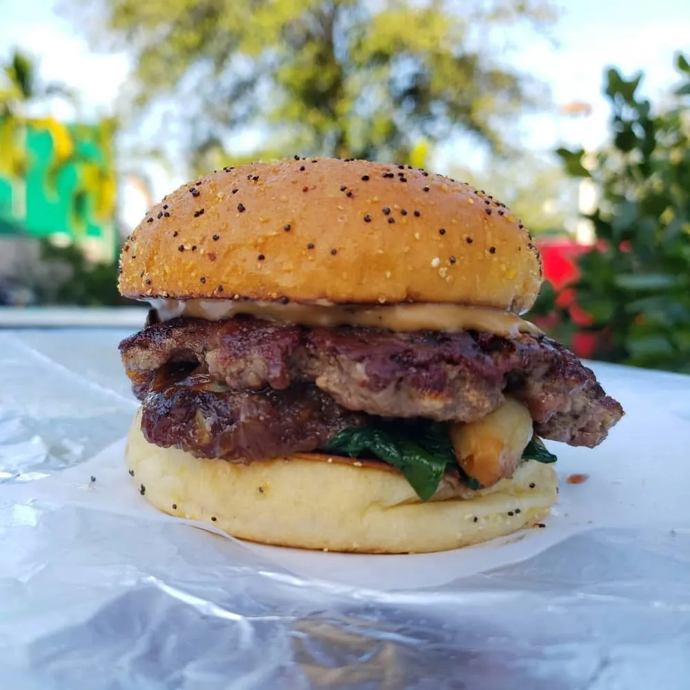 United States Burger Service smashburger showing caramelized crust, pickles, and cheese sauce
