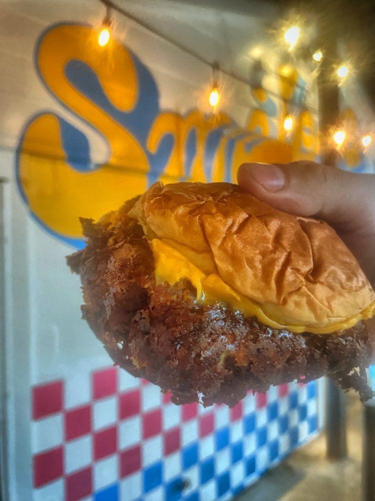 Smiley's Burger Club walk-up window with bright yellow signage in downtown Decatur