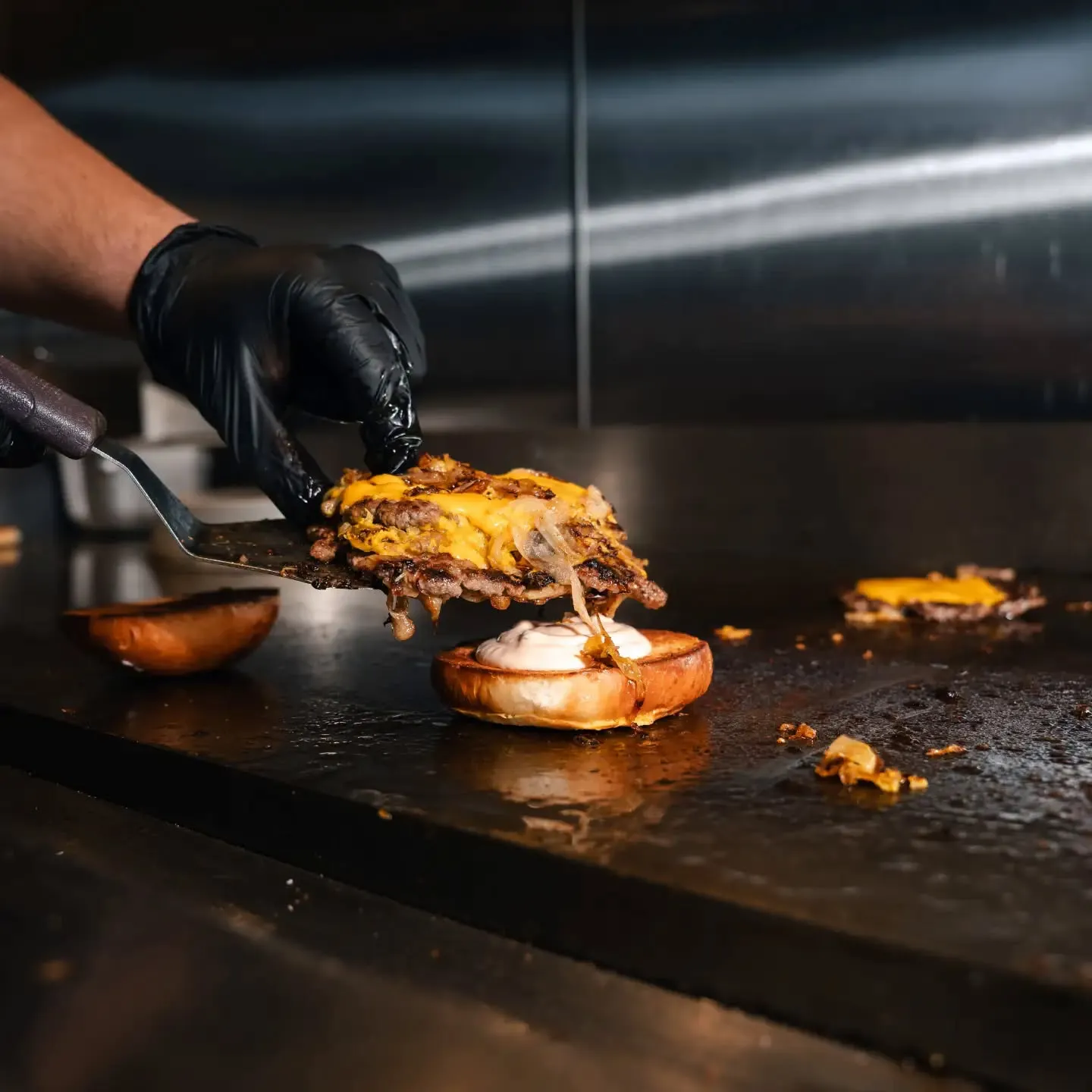 Ducky's at the Pearl smashburger being assembled on the griddle