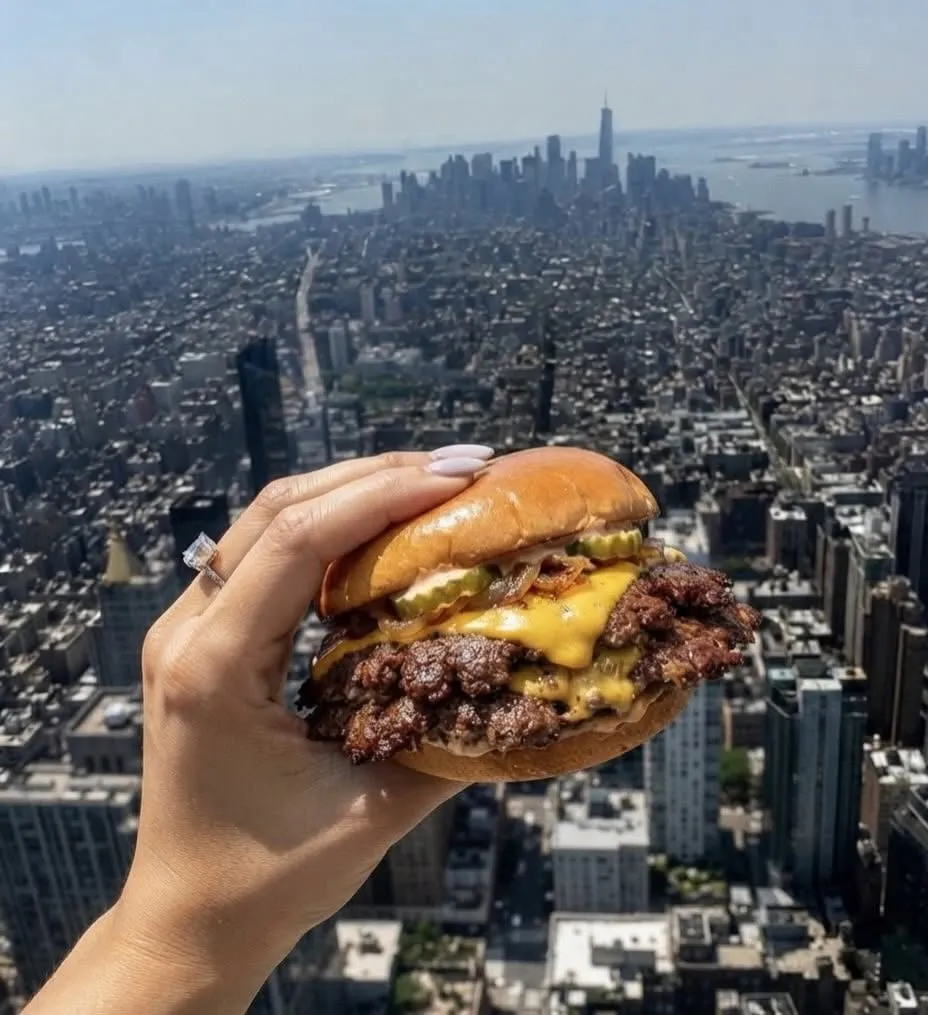 Bun N Done double smashburger held above the Manhattan skyline