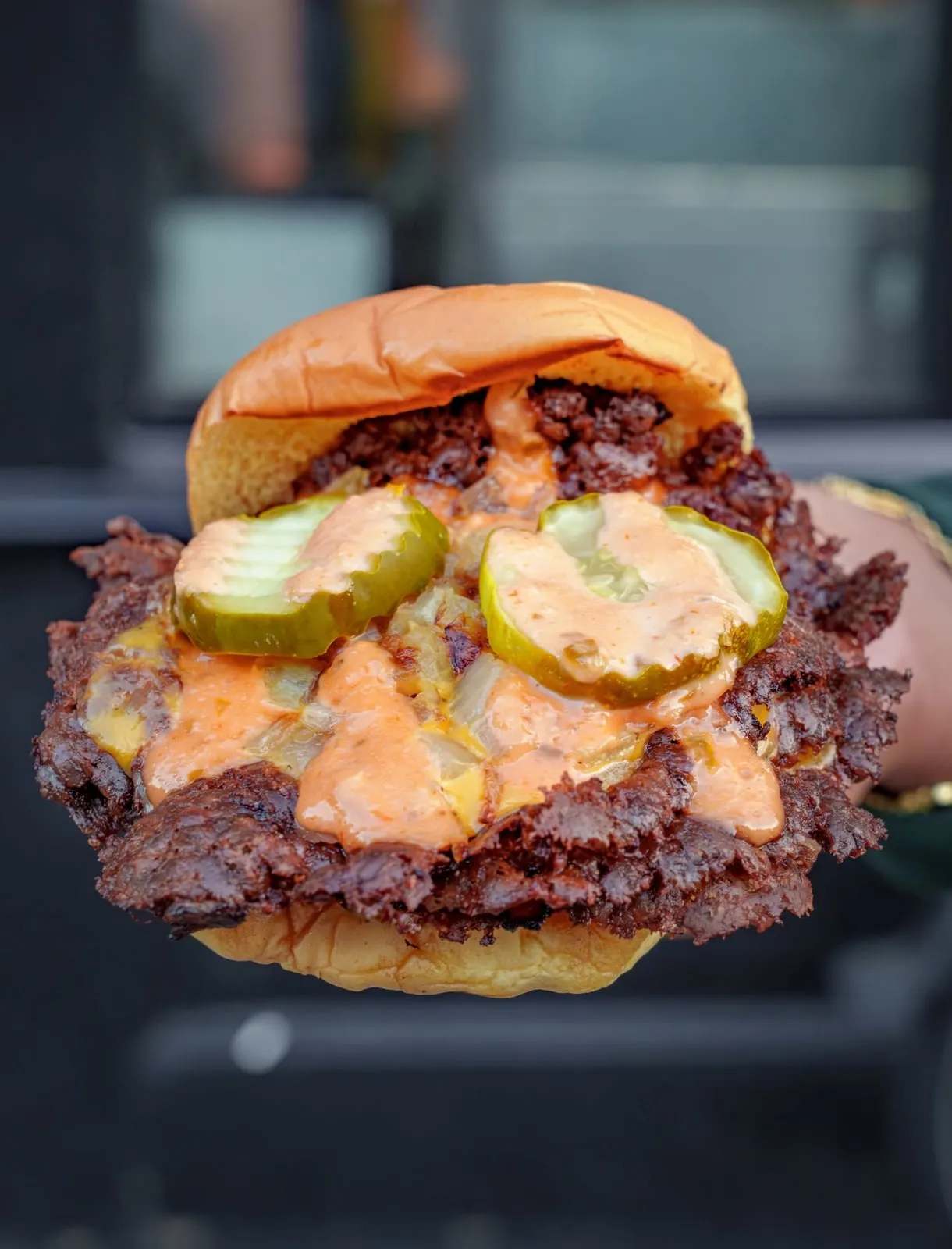 Close-up of the crispy-edged Dipped N' Smashed double burger with pickles and sauce