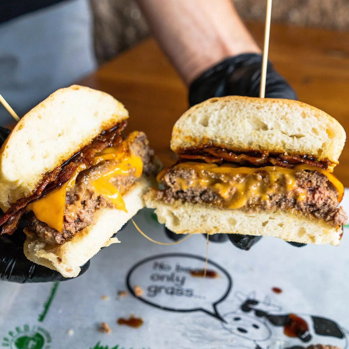 Two Dan & Day's bacon cheeseburgers cut open to show the grass-fed beef patties