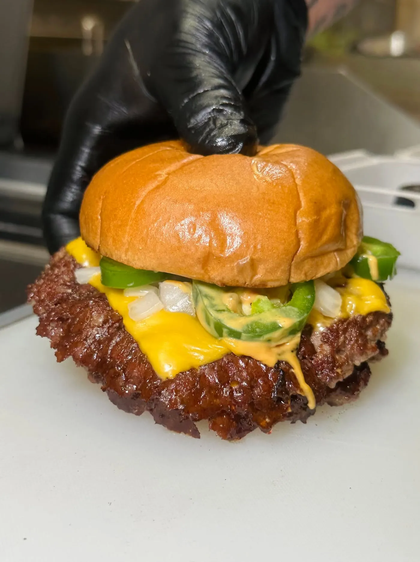 Burger Revolution smashburger being finished with a glossy bun