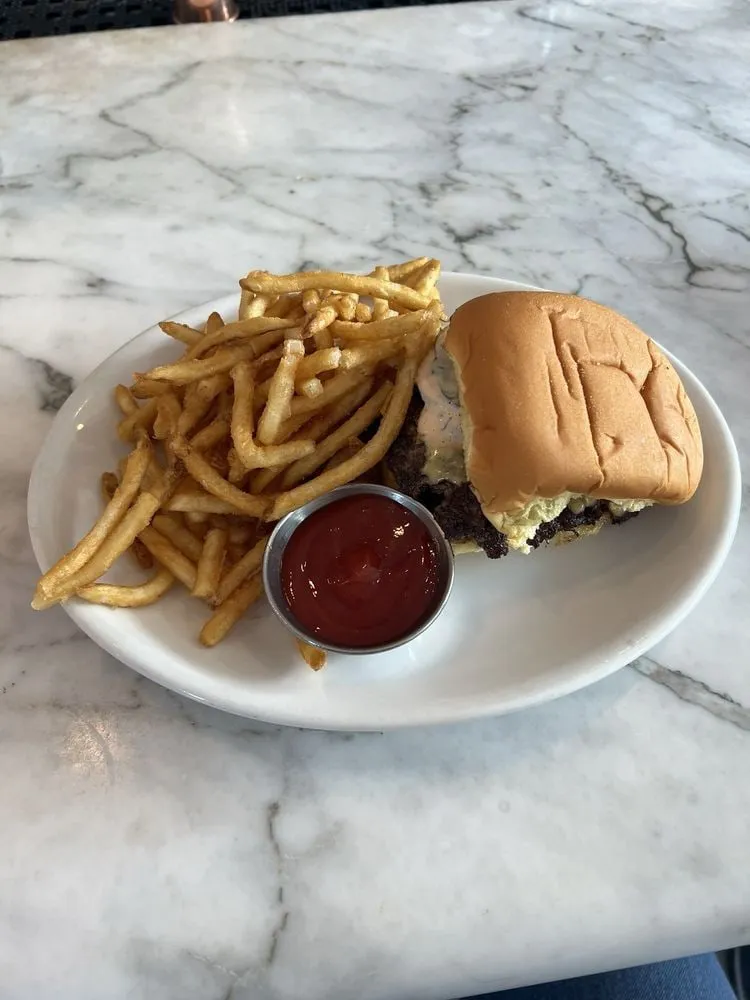 Cafe Roze smashburger served with fries on a marble table