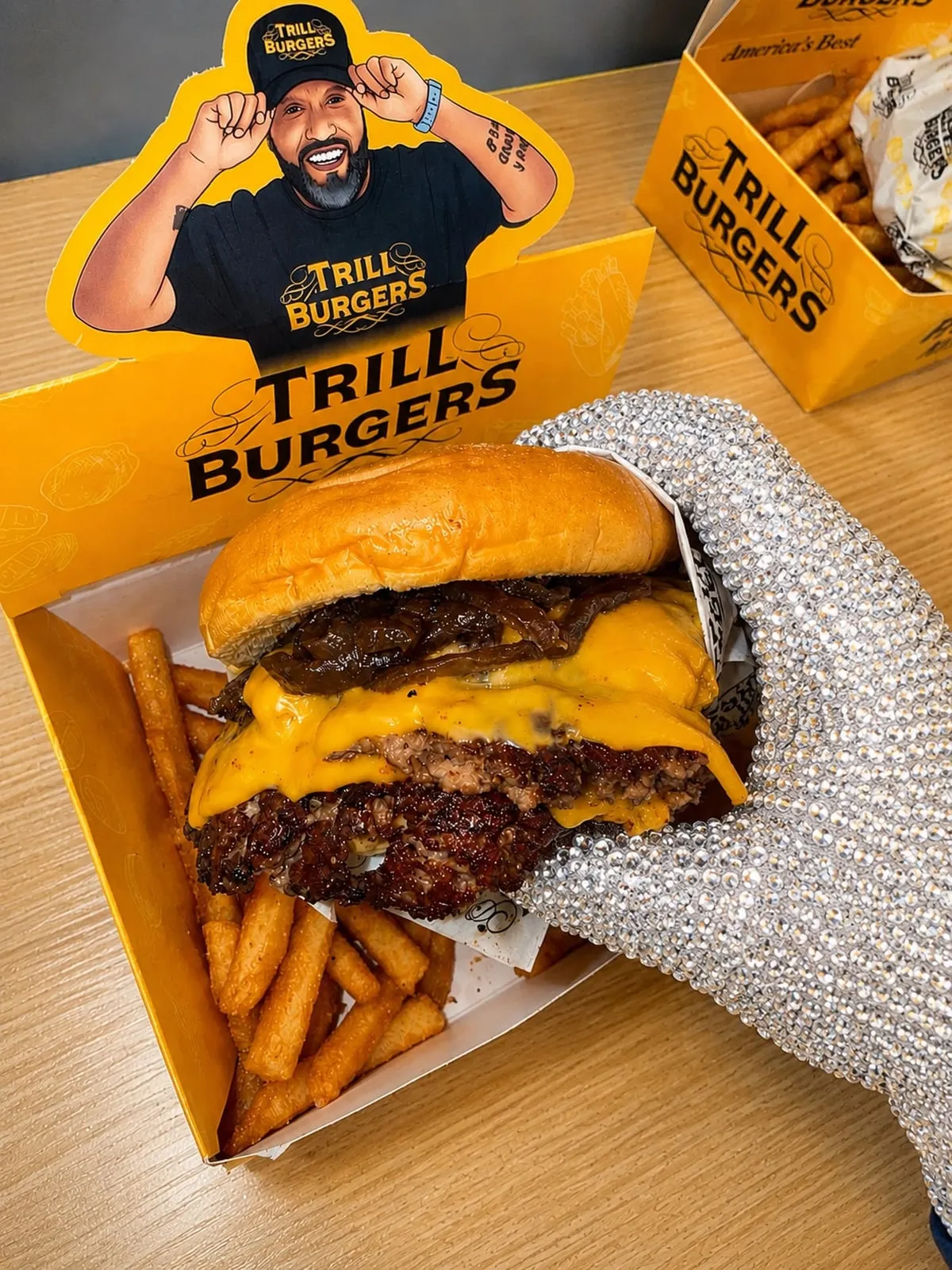 Branded Trill Burgers meal with a double cheeseburger, fries, and yellow packaging